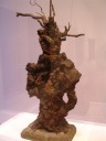 A wood and stone sculpture that resembles the upper half of a person.
Sadly, I don't know who the artist is.
