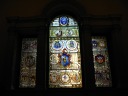 At the top of a set of stairs, a stained glass window displays all the
different versions of the seal of the state of Massachusetts.
