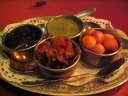 Chutneys and other accompaniments for the chapati.  Clockwise from left:
sweet mango chutney, mint chutney, sweet onions, and a lime/lemon
pickled thing.

