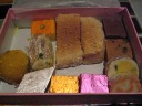 We bought a huge box of assorted goodies.  These would last
for many days. 
At some point, after processing my notes from each item we
tried as we ate it, I may return and label every item in this picture. 
The chhum chum is the silver and green sweet in the left half. 
The kesari dudh mathai is the yellow square. 
The khala khan is the metallic-looking, yellow square.  Cakey.  It's very good. 
The cashew barfi is the white diamond.  It's okay/decent.
