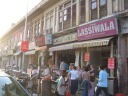 The real, original Lassiwalla is on the left of this picture, just to
the right of the Vodafone sign.  The others are fakes ones that sprung
up to take advantage of its success, imprecise or lazy or lost tourists,
and lack of enforcement of whatever trademark laws exist.  This
picture was taken the previous day when we attempted to visit Lassiwalla
and found it sold out.
