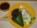My satays, along with accompanying fruits/vegetables.  The meat was so
well marinated, I preferred it dipless.  That said, the pictured dip was
a good home-made peanut dip with the right consistency; I just didn't
need it.  I don't know what the white-fleshed fruit was but do know it
was tasteless.  (It could use the dip!)  Also, there was a black soy
chilli "padi" dip (not pictured) that was really spicy.  (Indeed, if you
saw how much smaller that bowl was than this one, you'd guess how strong
it is.)

