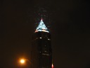 Seen more clearly in this longer-exposure photograph, it's clear those
flecks/streaks are some sort of avian creature flying circles around /
attracted to the top of the tower.
