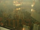 Looking south at Pudong's residential high-rises.  The Huangpu River is
at right.  The reflection in the glass is the inside of the
viewing deck.

