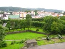 The estate-like Bergenhus Fortress, as seen from a higher fortress. 
Notice the stone walls and lines of trees.  You can also glimpse a bit
of the old port in the background.

