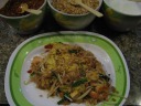 Pad thai, the staple Thai noodle dish.  I ordered mine with shrimp, which
were paste-y (yes, paste-y), not food at all (severe freezer burn?).  As
for the pad thai, it had much more egg than I'm used to seeing in the
states.  (I even looks vaguely like an omelette.)  As with most Thai
dishes I've had here, it was too sweet.  Also, I was a little scared as 
the woman added lots of chilies, but that worked out fine.

